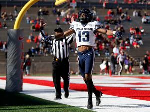 (Andres Leighton | AP) Utah State wide receiver Deven Thompkins (13) celebrates after scoring a touchdown against New Mexico during the first half of an NCAA college football game on Friday, Nov. 26, 2021, in Albuquerque, N.M.