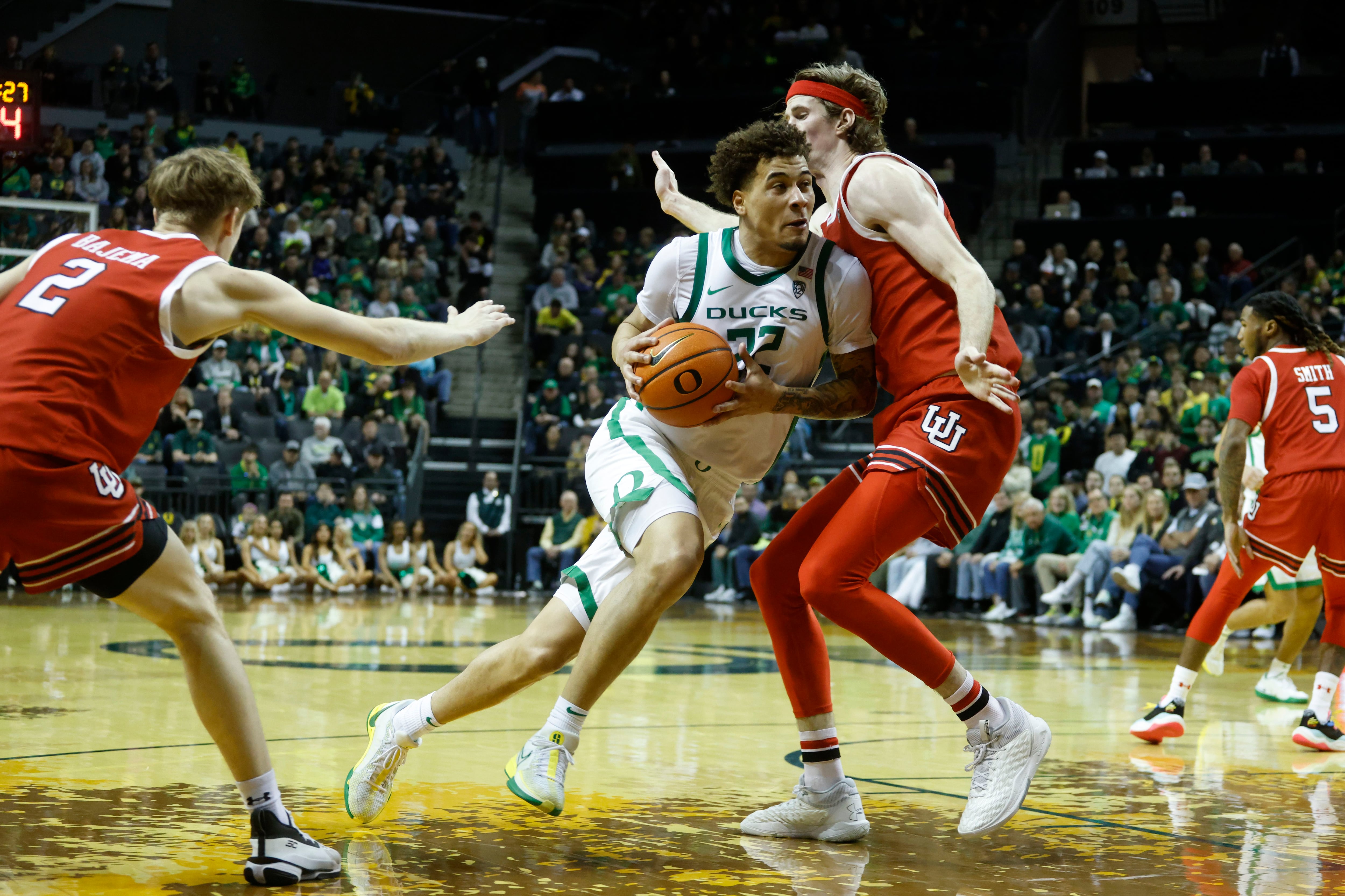 Oregon center Nate Bittle (32) drives against Utah guard Gabe Madsen (55) during the first half of an NCAA college basketball game in Eugene, Ore., Saturday, March 9, 2024. (AP Photo/Thomas Boyd)`