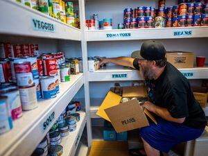 (Trent Nelson  |  The Salt Lake Tribune) Isaac McDonald stocks shelves in the food pantry at Crossroads Urban Center in Salt Lake City on Wednesday, June 29, 2022.