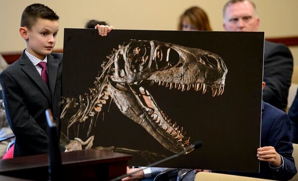 (Steve Griffin | The Salt Lake Tribune) Kenyon Roberts, 10, from Draper, holds a photograph of a Utahraptor on display at BYU, during testimony in front of the Senate Economic Development and Workforce Services Committee at the State Capitol in Salt Lake City, Friday, Feb. 2, 2018. S.B. 43 the State Dinosaur Amendment is looking to make the state dinosaur the Utahraptor.