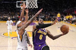 Los Angeles Lakers forward LeBron James, right, shoots as Utah Jazz guard Jordan Clarkson, center, and Danuel House Jr. defend during the first half of an NBA basketball game Wednesday, Feb. 16, 2022, in Los Angeles. (AP Photo/Mark J. Terrill)