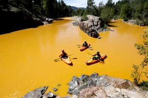 (Jerry McBride/The Durango Herald via AP) People kayak in the Animas River near Durango, Colo., in 2015, in water colored yellow from a mine waste spill. Colorado, the U.S. government and a gold mining company have agreed to resolve a longstanding dispute over who’s responsible for continuing cleanup at the site.