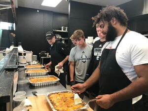 (Utah Foster Care) Nick Ford, right, a University of Utah offensive lineman, helps cook food at Cultivate Craft Kitchen during a Sunday dinner event with Utah Foster Care — one of the services the nonprofit provides to assist foster parents across the state.