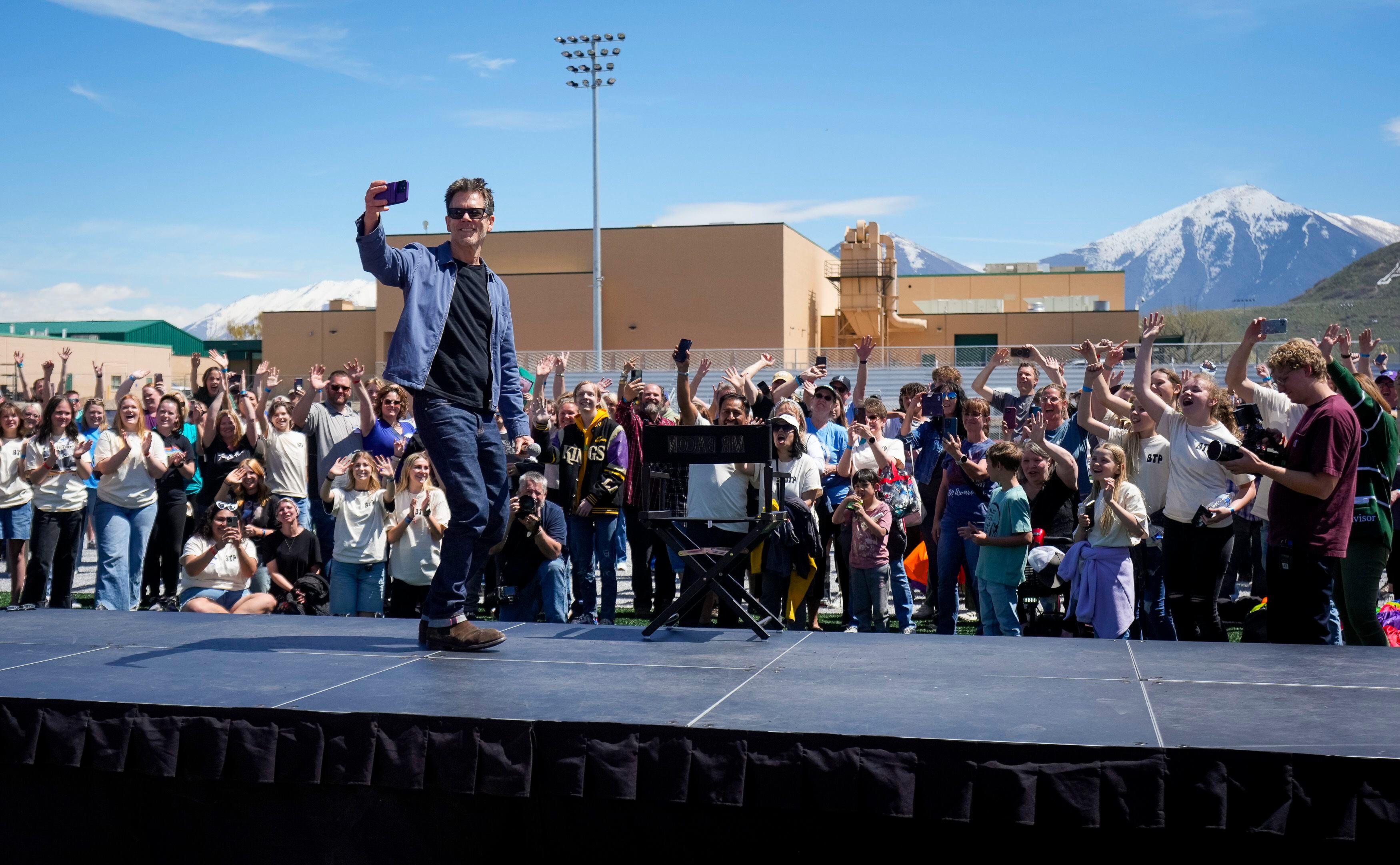(Bethany Baker  |  The Salt Lake Tribune) Kevin Bacon records a video with the crowd, playing into the "six degrees from Kevin Bacon" game, following a charity event to commemorate the 40th anniversary of the movie "Footloose" on the football field of Payson High School in Payson on Saturday, April 20, 2024.