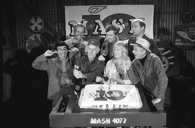 (Huynh | AP File Photo) In this Oct. 22, 1981, file photo, Jamie Farr, from front left, plugs his ears as cast members of the "M.A.S.H." television series cast Harry Morgan, Loretta Swit, William Christopher and, from back from left, Mike Farrell, Alan Alda and David Ogden Stiers celebrate during a party on the set of the popular CBS program in Los Angeles. 