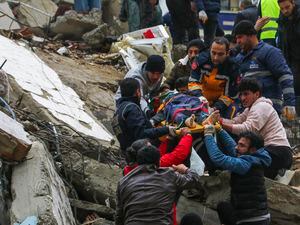 (IHA agency via AP) People and emergency teams rescue a person on a stretcher from a collapsed building in Adana, Turkey, Monday, Feb. 6, 2023. A powerful quake has knocked down multiple buildings in southeast Turkey and Syria and many casualties are feared.