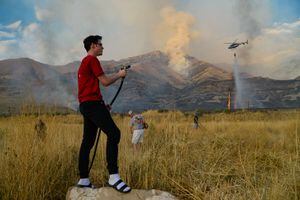 (Francisco Kjolseth  |  The Salt Lake Tribune)  Caden Terry, 15, does what he can as he joins neighbors in cutting down tall brush as crews battle a grass fire in Tooele county being dubbed the Green Ravine fire as it burns on Tuesday, Sept. 3, 2019.