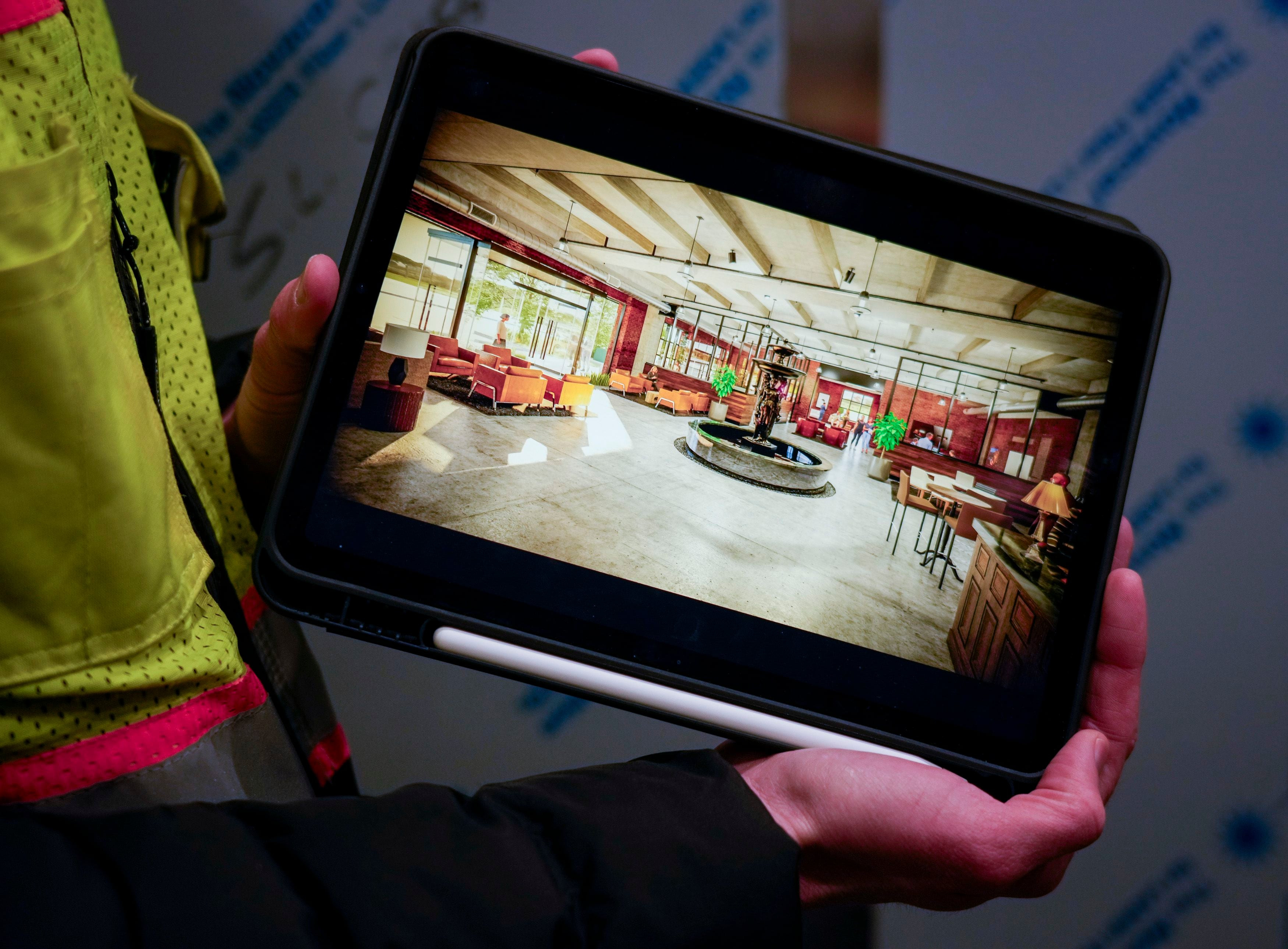 (Bethany Baker | The Salt Lake Tribune) Austin Vegh, the community manager for Salt Lake Crossing, holds up an iPad with a rendering of the lobby during a tour at the construction site for Salt Lake Crossing, a new apartment complex set to open in May, in downtown Salt Lake City on Friday, March 8, 2024.
