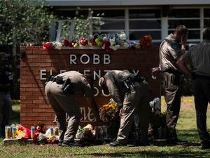(Jae C. Hong | AP) Two Texas Troopers light a candle at Robb Elementary School in Uvalde, Texas, Wednesday, May 25, 2022, after a mass shooting.