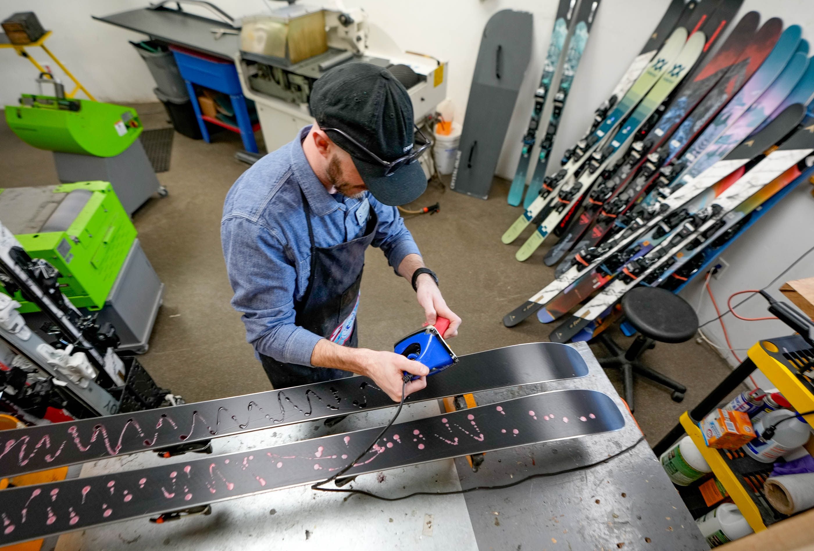 (Francisco Kjolseth  |  The Salt Lake Tribune) Bobby Monson, an area manager at Switchback Sports ski repair shop in Park City occasionally implements the older method of applying wax to skis, pictured Monday, April 1, 2024. The shop is doing its part in eliminating the use of high fluorocarbon waxes and Park City has banned the use of PFAS ski wax at their resorts for its effect on the environment.