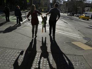 FILE - In a file photo, a child is lifted by her parents at a street corner in downtown Seattle.(AP Photo/Ted S. Warren, File)