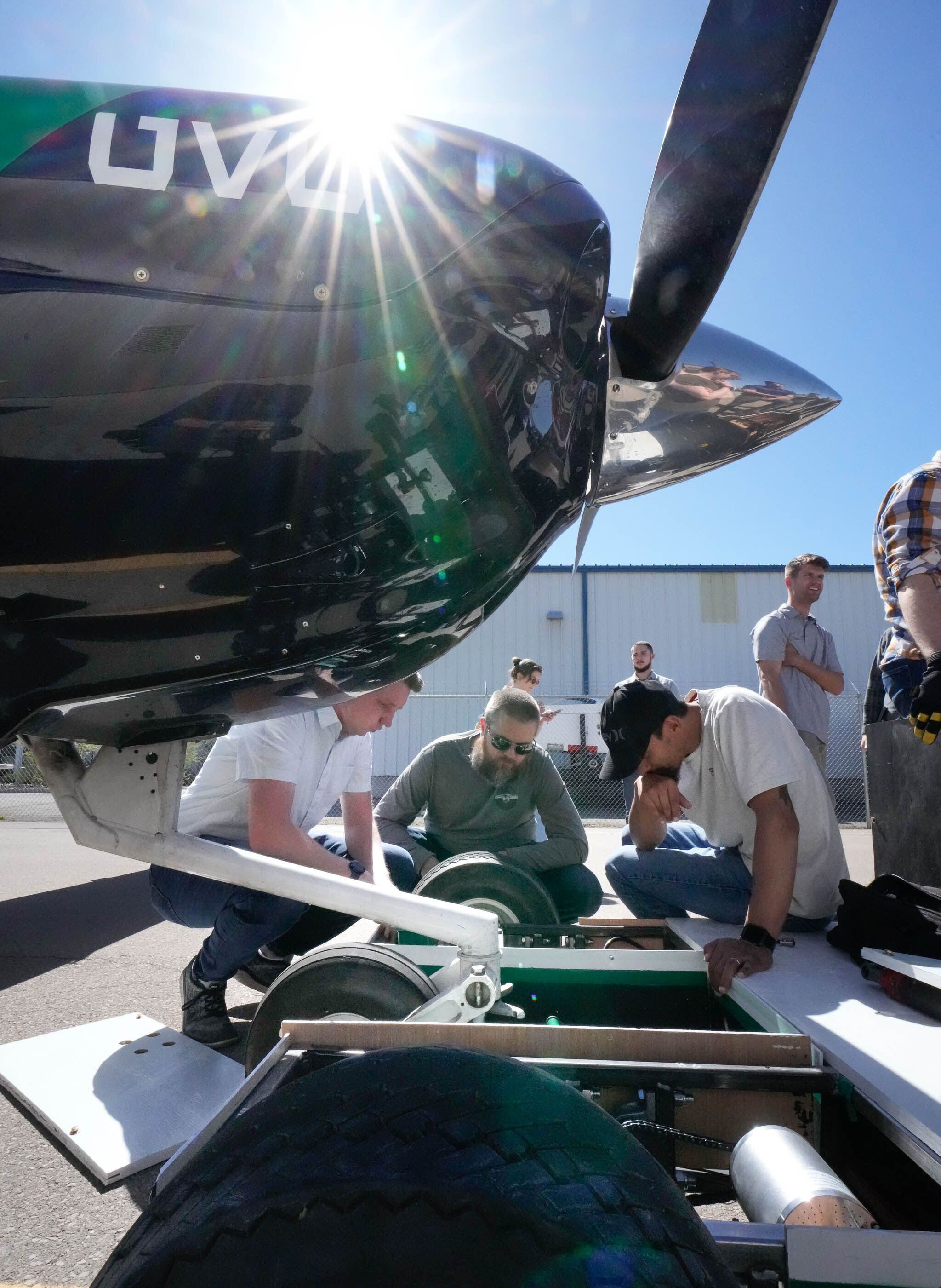 (Francisco Kjolseth | The Salt Lake Tribune) Utah Valley University students and professor Matt Jensen (center) troubleshoot a sprocket failure on a new prototype electric-powered, autonomous aircraft tug, during a demo at Provo Airport on Friday, April 12, 2024. The tug would cut down on airplanes needing to start their engines early by moving them around at busy airports and reducing emissions and jet fuel costs. 