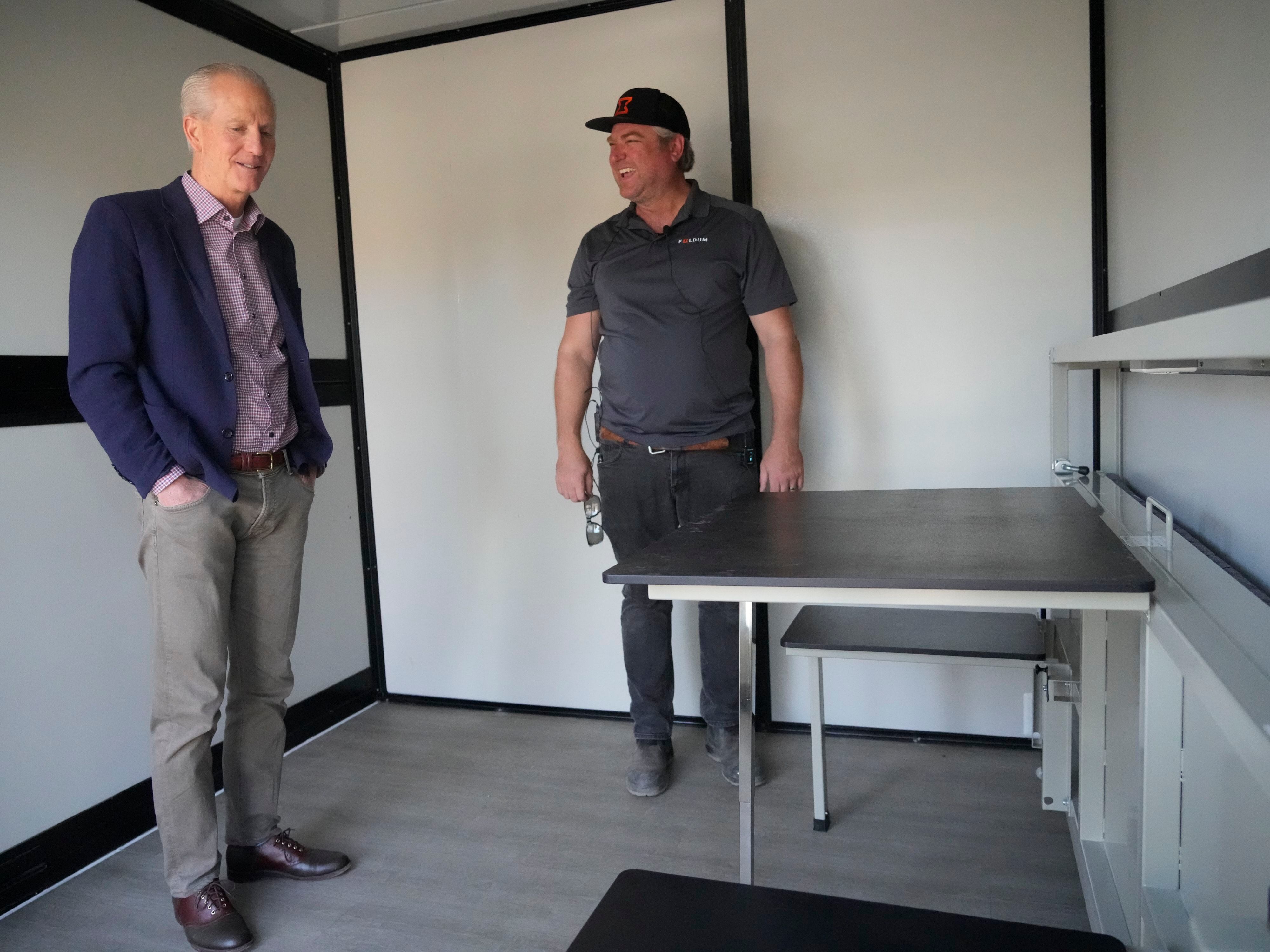 (Bethany Baker | The Salt Lake Tribune) Foldum Corp. CEO and co-founder Ryan Rossi, right, shows state homelessness coordinator Wayne Niederhauser, left, inside one of the units being used at the temporary legal homeless camp in Salt Lake City in November 2023. Niederhauser says he wouldn't oppose a measure raising the temperature for Utah's Code Blue law.