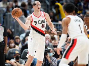 (David Zalubowski | AP) Portland Trail Blazers center Cody Zeller, back left, passes the ball to guard Anfernee Simons, front, as Denver Nuggets guard Bones Hyland defends in the second half of an NBA basketball game Sunday, Nov. 14, 2021, in Denver.