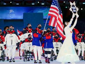 (Andy Wong | AP) Danelle Umstead and Tyler Carter of the United States carry the flag as they arrive for the opening ceremony at the 2022 Winter Paralympics, Friday, March 4, 2022, in Beijing.