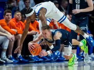 Boise State guard Chibuzo Agbo dives over Utah State guard Steven Ashworth in a scramble for the ball during the first half of an NCAA college basketball game Saturday, Jan. 7, 2023, in Boise, Idaho. (Darin Oswald/Idaho Statesman via AP)