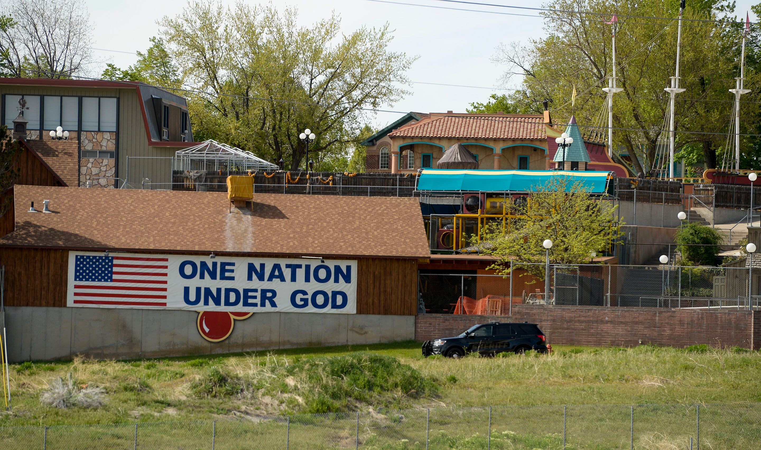 (Leah Hogsten | The Salt Lake Tribune) Cherries, from the Cherry Hill water park can barely be seen under a giant banner that reads, "One Nation Under God" in Farmington, April 29, 2020.