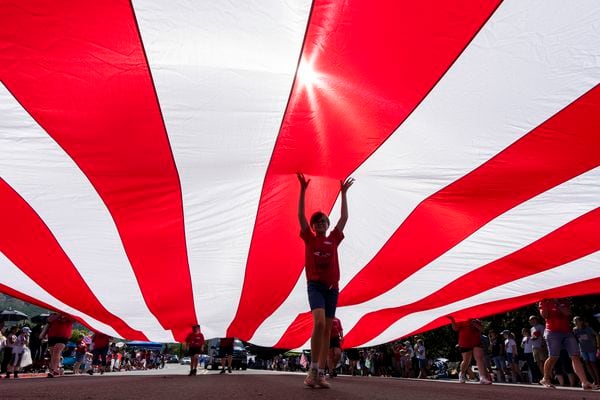 (Rick Egan | The Salt Lake Tribune) Marchers carry a giant American Flag in the Cherry Days Fourth of July Parade in North Ogden on Monday.