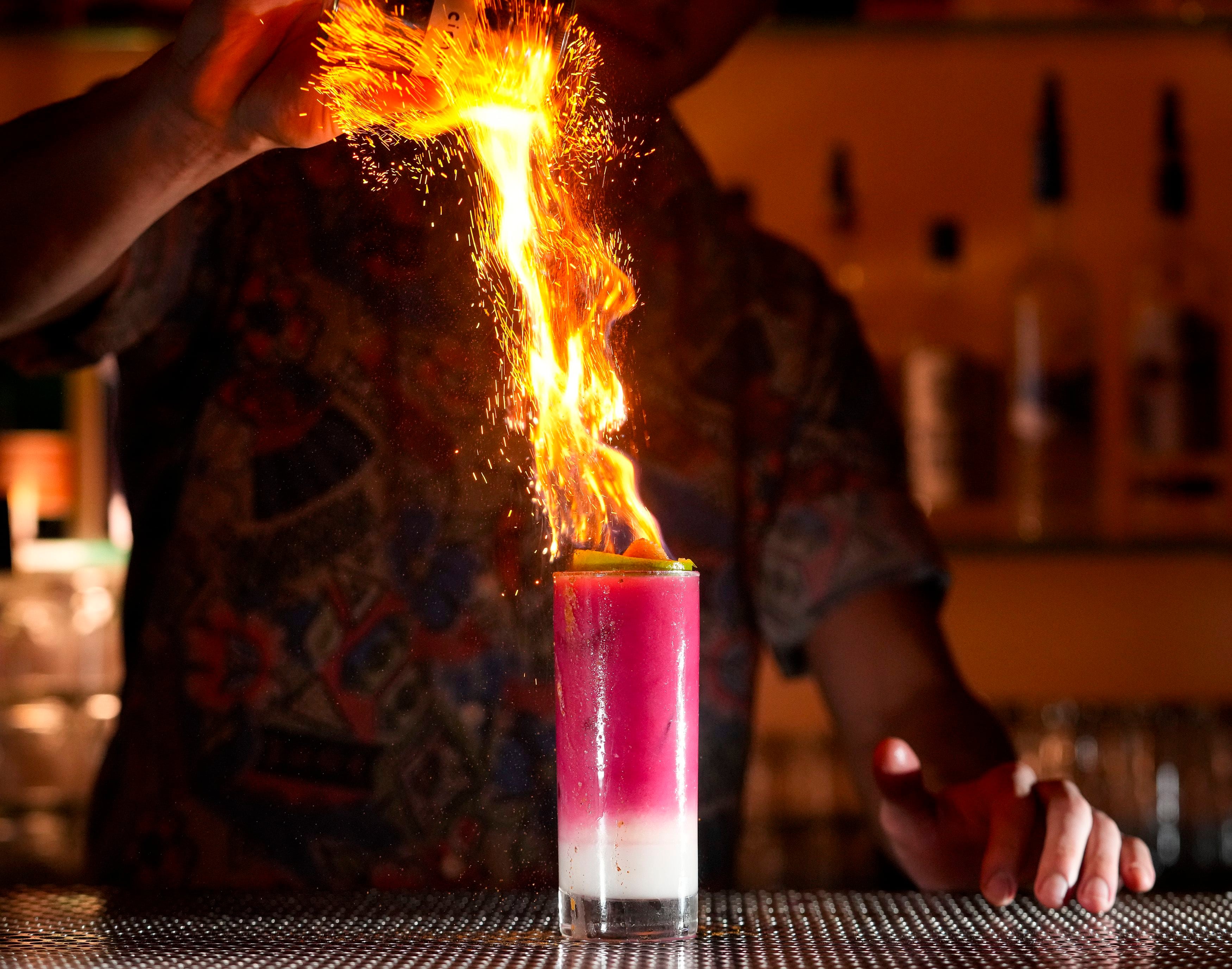 (Bethany Baker | The Salt Lake Tribune) Eric Lewis pours cinnamon over a craft mocktail drink for a fiery effect at Bar X in Salt Lake City on Thursday, Jan. 11, 2024.