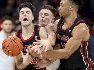 Arizona guard Pelle Larsson, center, is squeezed between Utah guards Lazar Stefanovic, left, and Marco Anthony, right, while fighting through a pick in the first half of an NCAA college basketball game in Tucson, Ariz., Saturday, Jan. 15, 2022. (Kelly Presnell/Arizona Daily Star via AP)