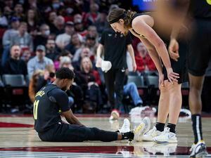 Utah Jazz forward Kelly Olynyk, right, talks to guard Mike Conley, who sits on the court after being injured during the second half of the team's NBA basketball game against the Portland Trail Blazers in Portland, Ore., Saturday, Nov. 19, 2022. (AP Photo/Craig Mitchelldyer)
