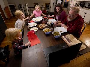 Jessica and John Franz pray before Thanksgiving dinner with their daughters, Quinn, 2, left; Amelia, 11; and Molly, 8, back, Thursday, Nov. 26, 2020, in Olathe, Kan. The family was having a quiet scaled-back Thanksgiving with just their household due to concerns about the coronavirus. (AP Photo/Charlie Riedel)