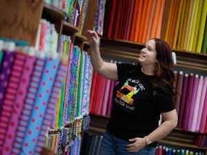 (Francisco Kjolseth | The Salt Lake Tribune) Whitney Warner, store manager at My Girlfriend’s Quilt Shoppe in Sandy, overlooks the fabric selections, Wednesday, Oct. 12, 2022.