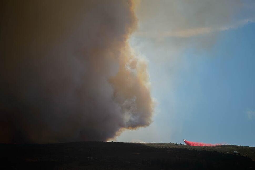 (Trent Nelson | The Salt Lake Tribune) A plane dropping retardant on the Dollar Ridge Fire is dwarfed by smoke, in Duchesne County, Tuesday July 3, 2018.