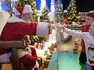 (AP Photo/Seth Wenig) Julianna, 3, and Dylan Lasczak, 5, visit with Santa through a transparent barrier at a Bass Pro Shop in Bridgeport, Conn., on Nov. 10, 2020. In this socially distant holiday season, Santa Claus is still coming to towns (and shopping malls) across America but with a few 2020 rules in effect.