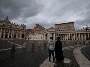 (AP Photo/Alessandra Tarantino) FILE - Two people stand in an empty St.Peter's Square, at the Vatican, as Pope Francis recites the Angelus noon prayer in his studio Friday, Jan. 1, 2021. The Vatican indicted 10 former officials and business partners on Saturday, including a cardinal, in connection with a controversial investment in property in London that depleted the church’s finances and undermined its credibility.