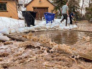 (Trent Nelson  |  The Salt Lake Tribune) People work to save a home as Emigration Creek rises in Emigration Canyon on Wednesday, April 12, 2023. As public officials have urged Utahns to prepare for flooding by purchasing insurance policies, thousands may not have access to it and few communities participate in a federal program to make it more affordable.