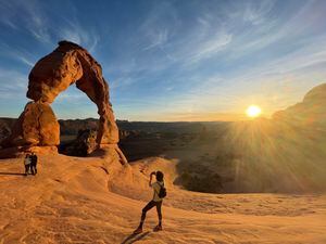 (NPS / Nicole Segnini)
A couple takes a picture at Delicate Arch during sunset. Many hikers suffer heat-related issues along the trail even though it is only 3 miles round trip.