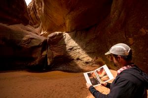 (Rick Egan | The Salt Lake Tribune) Glen Canyon Institute executive director Erik Balken compares the "Cathedral in the Desert" in Clear Creek Canyon with photos in a historical photo journal of Glen Canyon, on Monday, May 17, 2021.