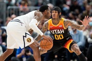 Denver Nuggets forward Will Barton, front, looks to pass the ball as Utah Jazz guard Jordan Clarkson defends in the second half of an NBA basketball game Sunday, Jan. 16, 2022, in Denver. (AP Photo/David Zalubowski)