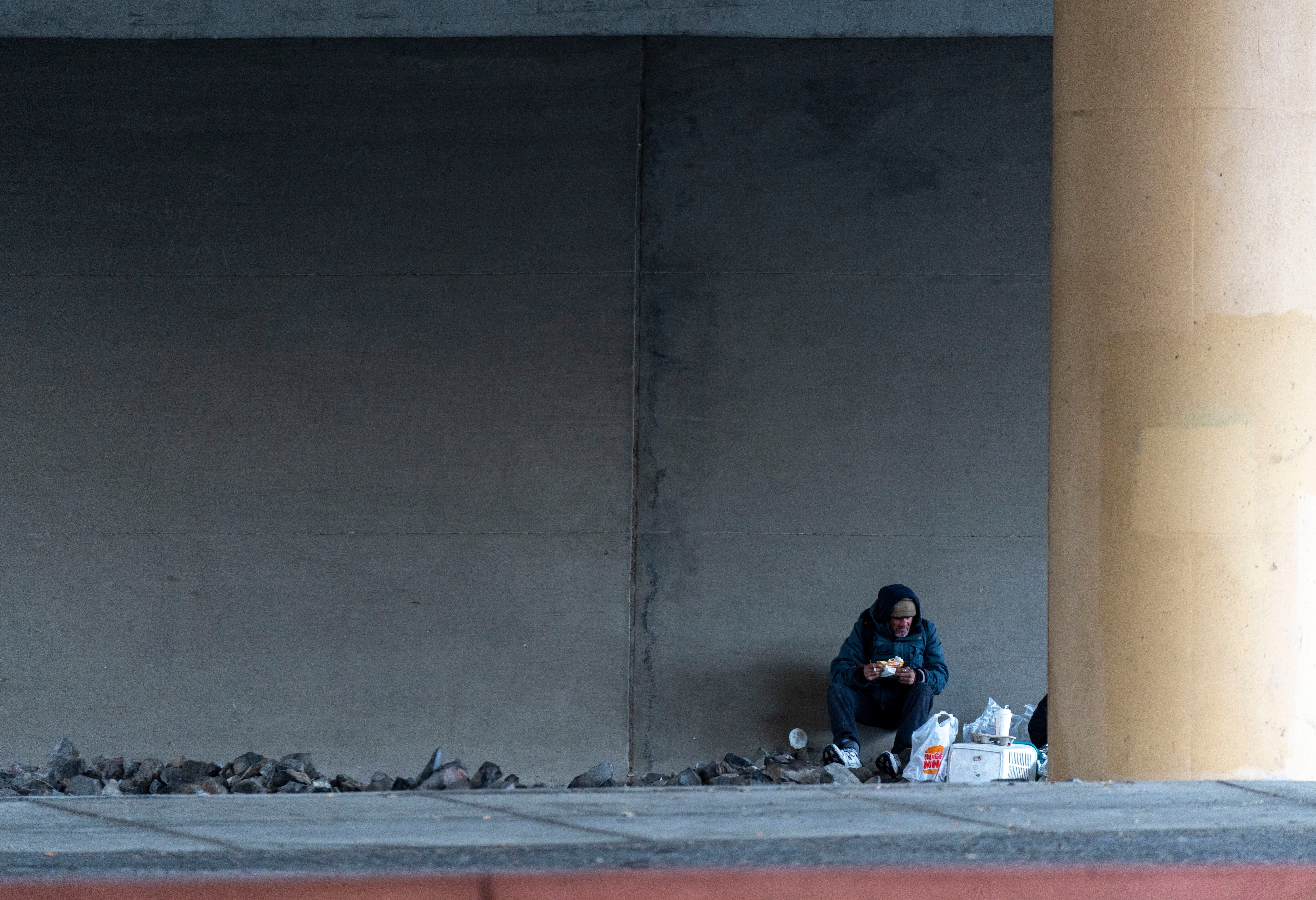 (Rick Egan | The Salt Lake Tribune) A man seeks shelter from the snow under the overpass on North Temple on Friday, Jan. 5, 2024. When temperatures fall to 15 degrees or below, a Code Blue law allows winter shelters to expand their allowable capacity.
