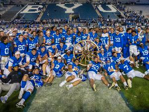 (Rick Egan | The Salt Lake Tribune) The Brigham Young Brigham Young Cougars pose for a photo with the Wagon Wheel, after they defeated the Utah State Aggies 38-26, at LaVell Edwards Stadium in Provo, on Thursday, Sept. 29, 2022.