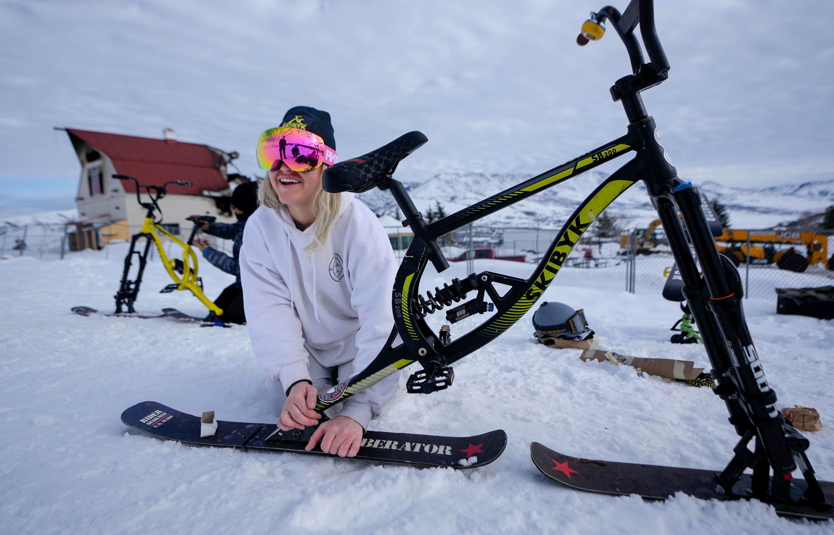 (Francisco Kjolseth | The Salt Lake Tribune) Kierra Keller of Tahoe adjusts her ski bike before preparing for a biker cross event at Nordic Valley Ski Resort in Weber County on Friday, Jan. 19, 2024. The resort’s main lodge, in background, burned earlier in the week placing the event in question. However, in an effort to keep things going despite numerous challenges, the resort pressed on with the event. 