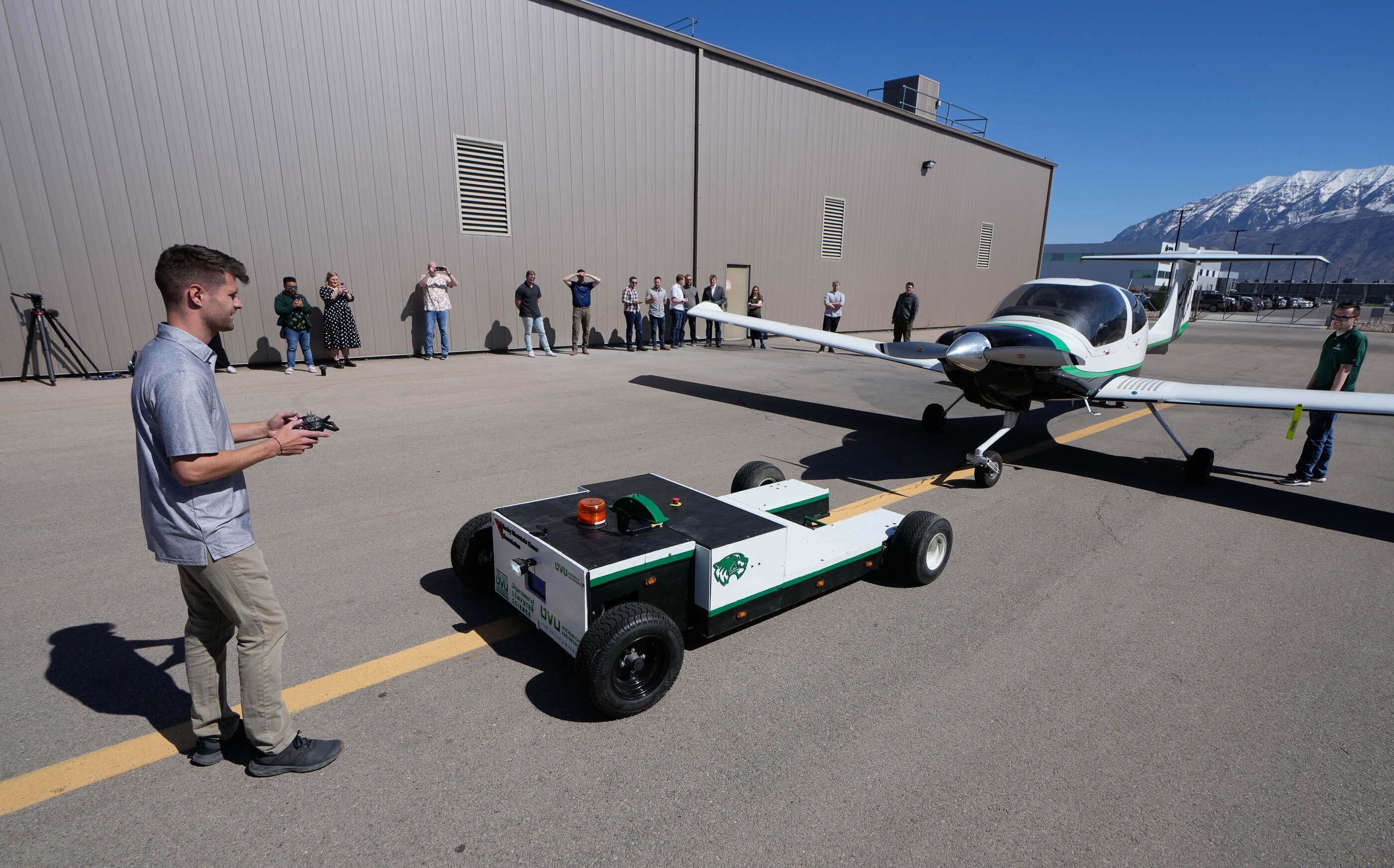 (Francisco Kjolseth | The Salt Lake Tribune) Utah Valley University computer science student Cache Fulton uses a controller to pilot an autonomous, electric-powered aircraft tug during a demo at Provo Airport on Friday, April 12, 2024. The tug would cut down on airplanes needing to start their engines early by moving them around at busy airports and reducing emissions and jet fuel costs. 