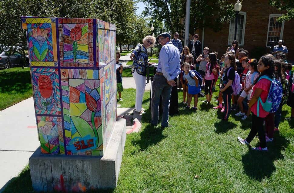 (Francisco Kjolseth | The Salt Lake Tribune) Mayor Jackie Biskupski joins Bennion Elementary art teacher Paul Heath as he talks about his students art work that now decorates a utility box near the school. Salt Lake City schools alongside Bennion Elementary school kids and the mayor unveiled the final phase of its ColorSLC program, on Tuesday, Aug. 20, 2019, in which artwork from each of the district's elementary schools decorated utility boxes near each school.