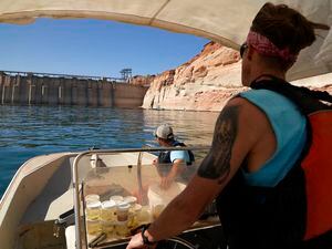 (Brittany Peterson | AP file photo) Utah State University master's student Barrett Friesen steers a boat near Glen Canyon dam on Lake Powell on June 7, 2022, in Page, Ariz. Six western states that rely on water from the Colorado River have agreed on a plan to dramatically cut their use. California, the state with the largest allocation of water from the river, is the holdout.