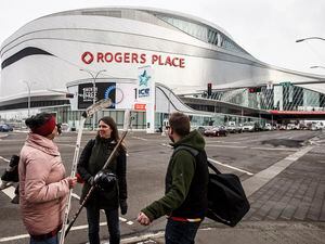 FILE - In this March 12, 2020, file photo, people talk outside Rogers Place, the home ice of the NHL hockey club Edmonton Oilers, in Edmonton, Alberta. (Jason Franson/The Canadian Press via AP, File)