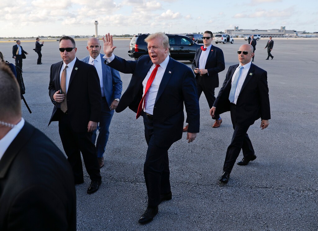 President Donald Trump, center, surrounded by members of the Secret Service, walks across the tarmac to begin to greet supporters during his arrival at Palm Beach International Airport, Thursday, April 18, 2019, in West Palm Beach, Fla. Trump traveled to Florida to spend the Easter weekend as his Mar-a-Lago estate. (AP Photo/Pablo Martinez Monsivais)