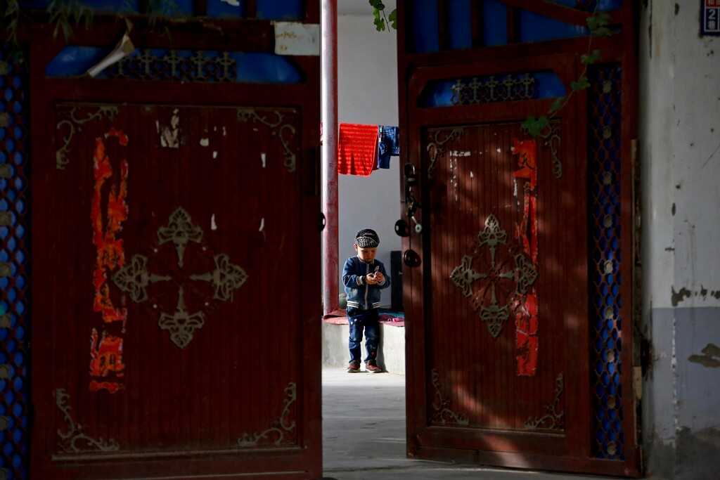 (AP Photo/Andy Wong) In this Sept. 20, 2018, photo, an Uighur child plays alone in the courtyard of a home at the Unity New Village in Hotan, in western China's Xinjiang region. The hundreds of millions of dollars the government pours into birth control have transformed Xinjiang from one of China’s fastest-growing regions into one of its slowest in just a few years, according to new research obtained by The Associated Press in advance of publication by China scholar Adrian Zenz.