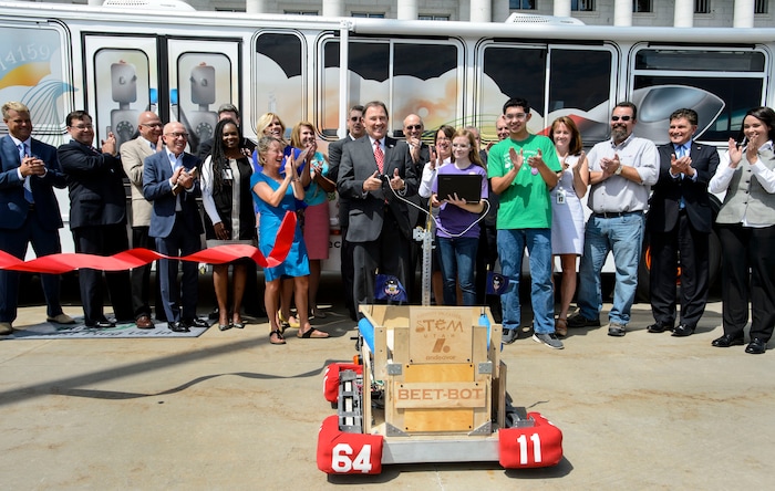 (Steve Griffin | The Salt Lake Tribune) Jordan High School's FIRST Robotics Team members Nicole Brooks and Ethan Nielsen, center right, help Gov. Gary Herbert cut a red ribbon with their gold scissor equipped Beet Bot during ceremony by the Utah STEM Action Center to celebrate the launch of the Utah STEM Bus into the 2016-2017 school year. The Center transformed a donated Utah Transit Authority bus into a mobile classroom to bring hands-on science, technology, engineering and math experiences to Utah students.