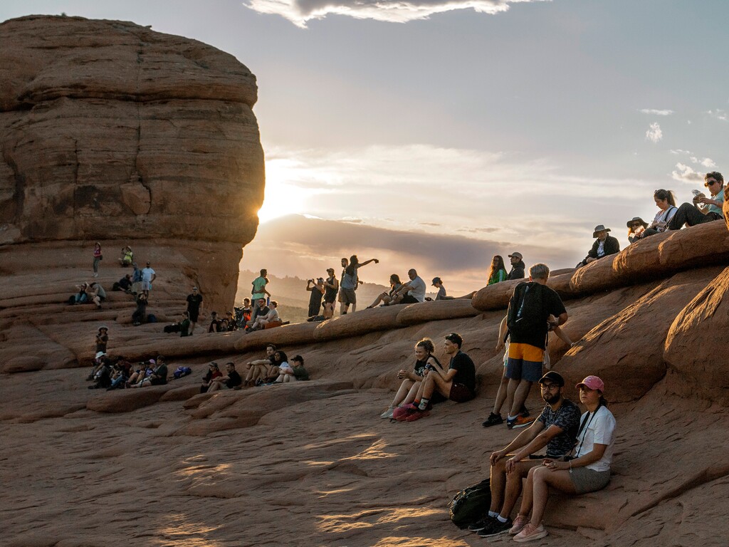 (Leah Hogsten | The Salt Lake Tribune) Visitors to Delicate Arch in Arches National Park hang out around the Entrada Sandstone formation as the sun sets, Tuesday, May 16, 2023. In April 2023, Arches National Park implemented a timed entry system to pace visitors' arrival times to alleviate overcrowding and congestion among some 1.8 million visitors a year.