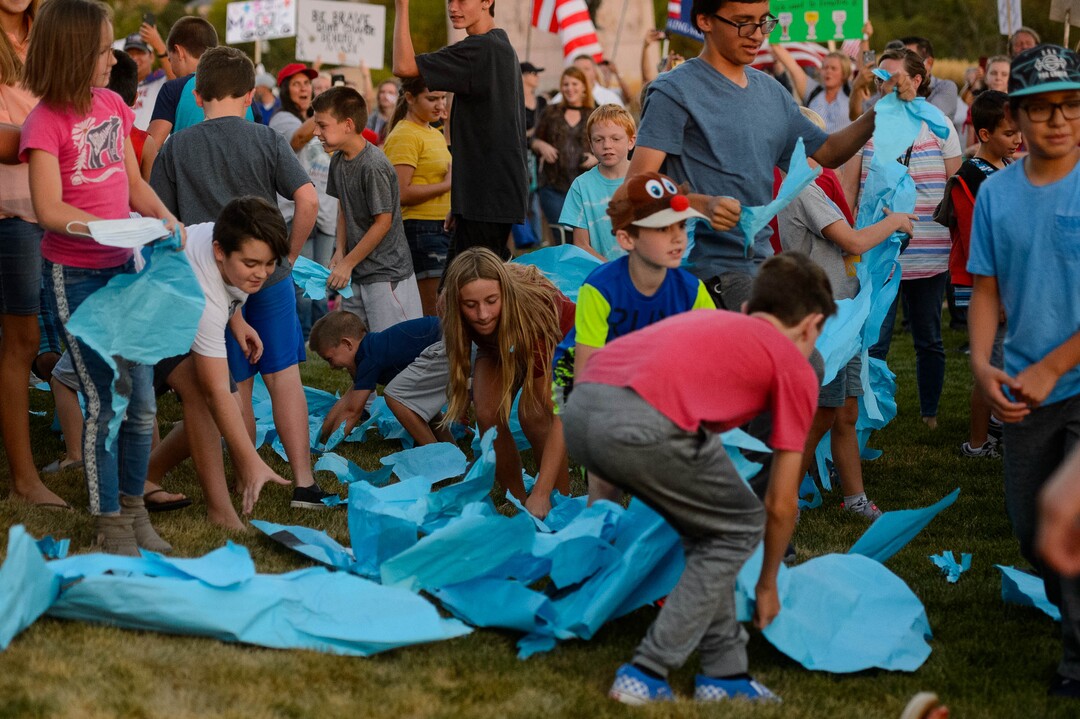 (Trent Nelson  |  The Salt Lake Tribune) Children rip up a large blue mask at a rally protesting government mask mandates at the State Capitol in Salt Lake City on Saturday, Sept. 5, 2020.
