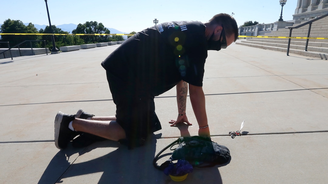 Shane Brooks, a Marine Corps veteran, kneels for nine hours outside the Utah Capitol to call attention to racial injustice, police brutality and mental health, Thursday, Aug. 6, 2020, in Salt Lake City. Brooks said people of color with mental illness are "looked at as if they have already committed a crime" and some end up dead in encounters with police, KTVX-TV reported. Brooks said his marathon silent protest was inspired by Bobby Duckworth, a 26-year-old who was shot and killed in 2019 by police responding to a report of a suicidal person in Wellington, Utah. (AP Photo/Rick Bowmer)