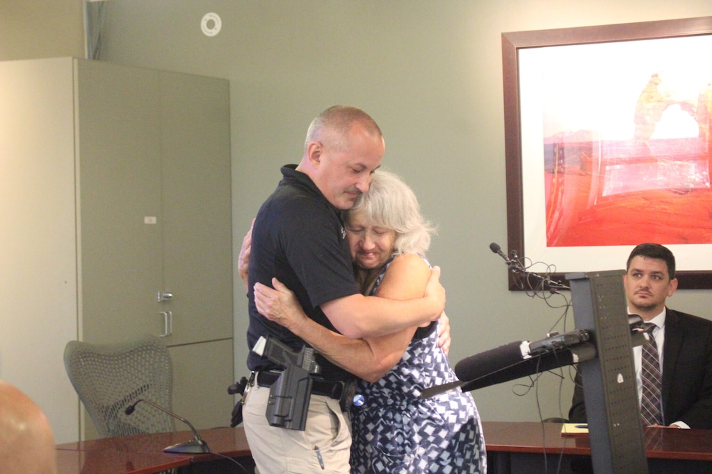 (Doug McMurdo | The Times-Independent) Leslie Ann Estes, the eldest child and last remaining sibling of Ann and Leslie “Woody” Woodward, hugs Moab Police Detective Jeremy Drexler at the conclusion of Friday’s press conference.