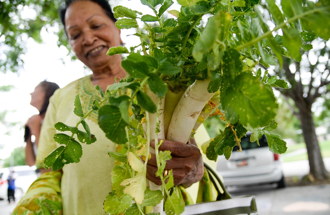 (Francisco Kjolseth  |  The Salt Lake Tribune)  Prommila Almas of Pakistan pics out vegetables she says are good for the kidneys as she visits the Sunnyvale Farmers Market at 4013 S. 700 West, which draws a weekly refugee clientele on Saturday, July 13, 2019, selling food grown exclusively by refugees living in Utah.