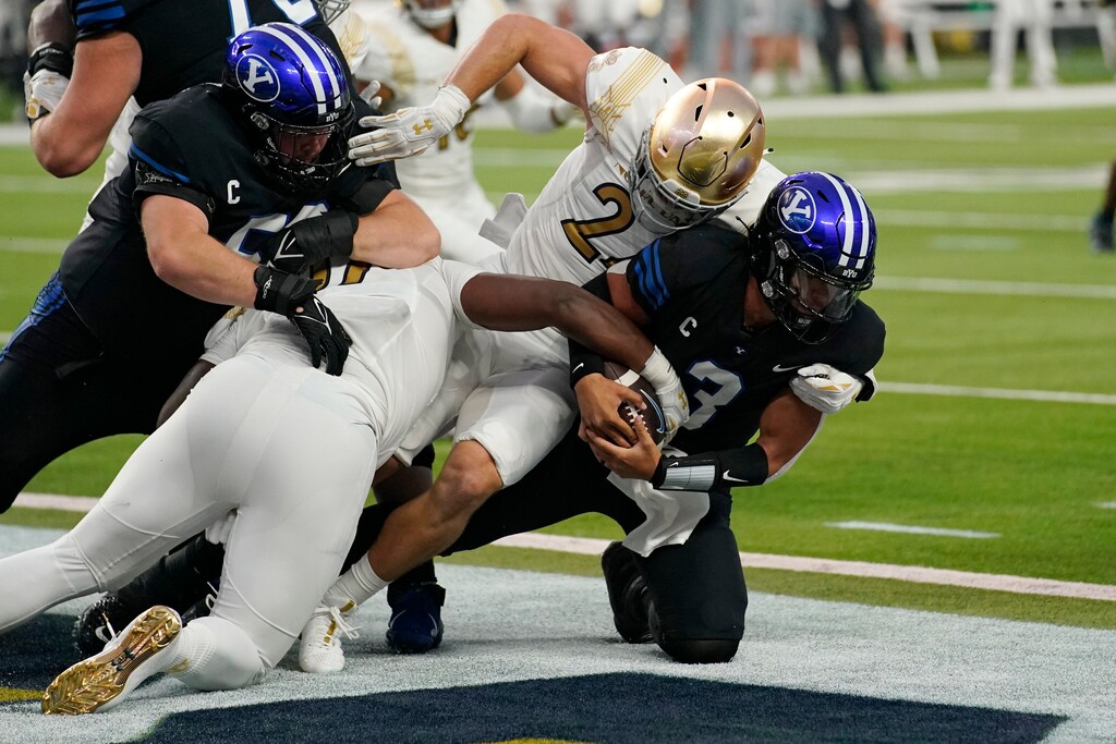 (John Locher | AP) Notre Dame defensive lineman Jayson Ademilola, bottom left, and linebacker Jack Kiser (24) sack BYU quarterback Jaren Hall for a safety during the first half of an NCAA college football game Saturday, Oct. 8, 2022, in Las Vegas.